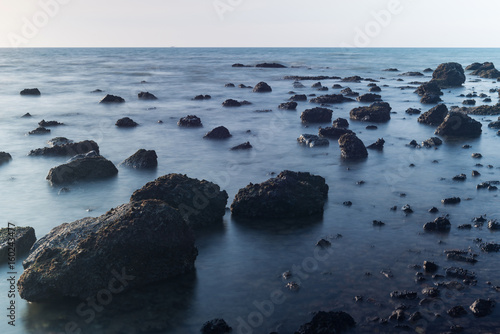 Beautiful landscape sunset in the sea with stones rocks on long exposure