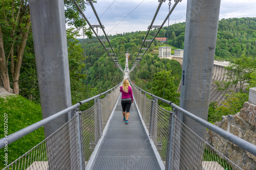 Fototapeta Naklejka Na Ścianę i Meble -  Girl walking over a suspension bridge