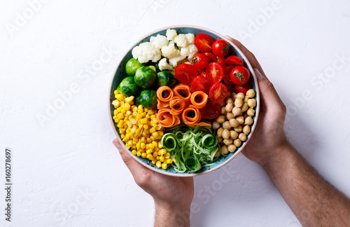 Raw mixed Vegetables and chickpeas on a white. Background Vegetarian Buddha Bowl in the Men's Hands. Food or Healthy diet Concept.Super Food.Copy space for Text. selective focus.
