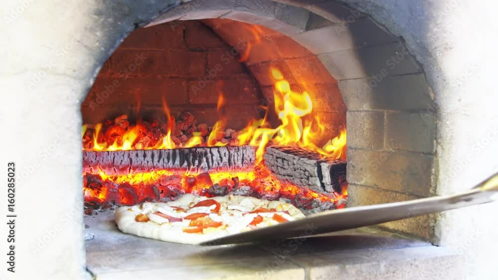 Pizza being baked in traditional wood burning pizza-bread oven in a restaurant. Pizza being baked in traditional wood burning pizza-bread oven in a restaurant.
