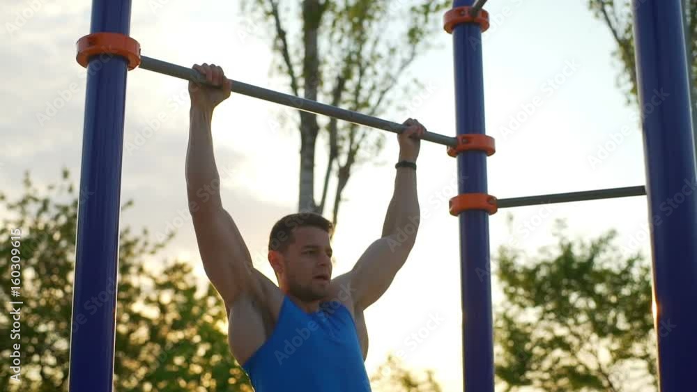 Strong fit man doing pull ups on horizontal bar park sunrise workout slow motion Strong fit man doing pull ups on horizontal bar park sunrise workout slow motion