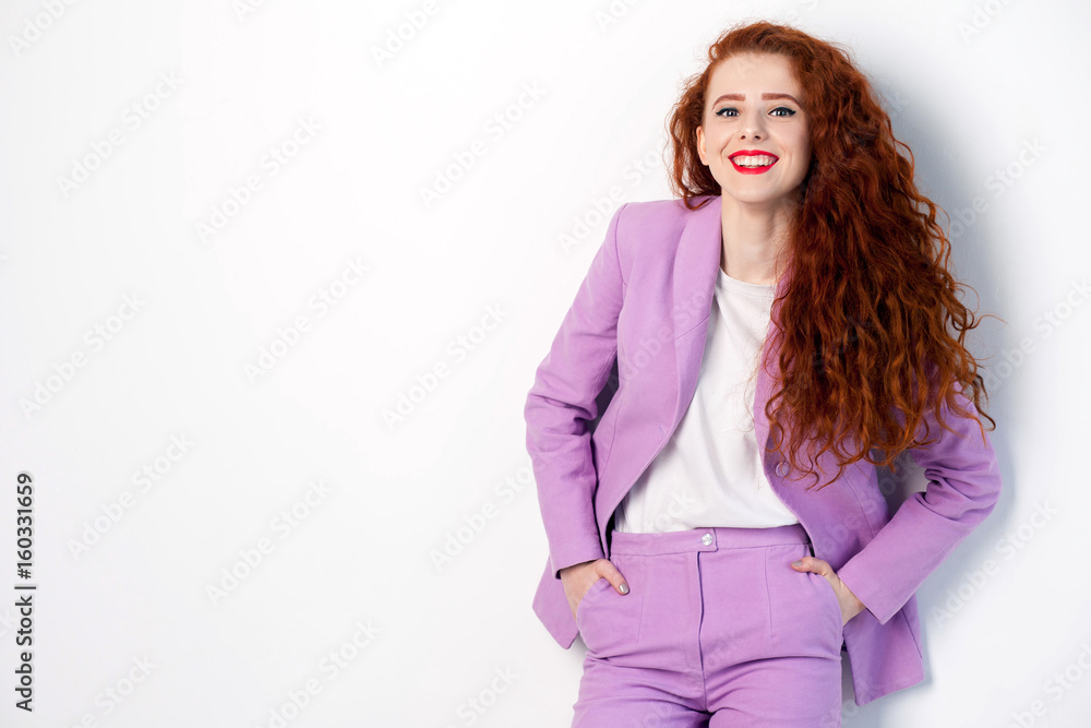 Portrait of successful happy beautiful business woman with red - brown hair and makeup in pink suit. looking at camera with toothy smile, studio shot on gray background. Portrait of successful happy beautiful business woman with red - brown hair and makeup in pink suit. looking at camera with toothy smile, studio shot on gray background.