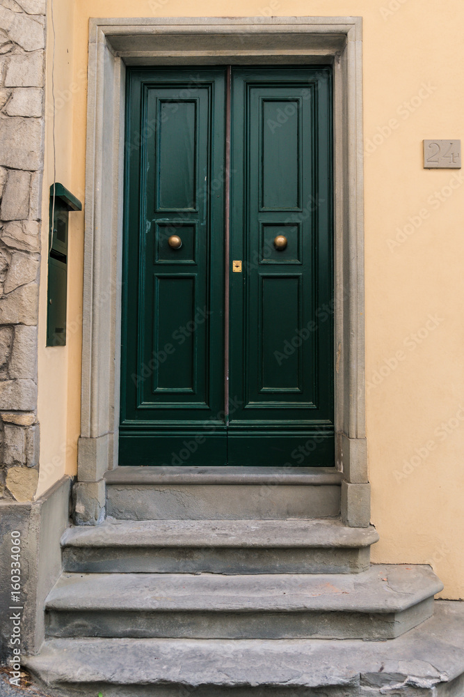 Green door with three stone steps in front in Fiesole, Italy