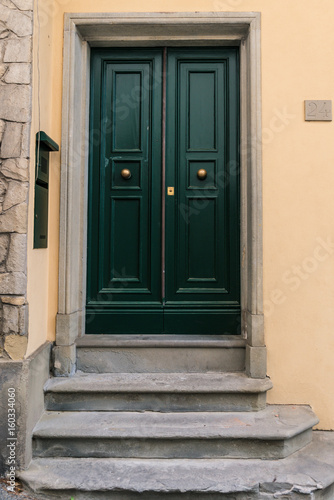 Green door with three stone steps in front in Fiesole, Italy