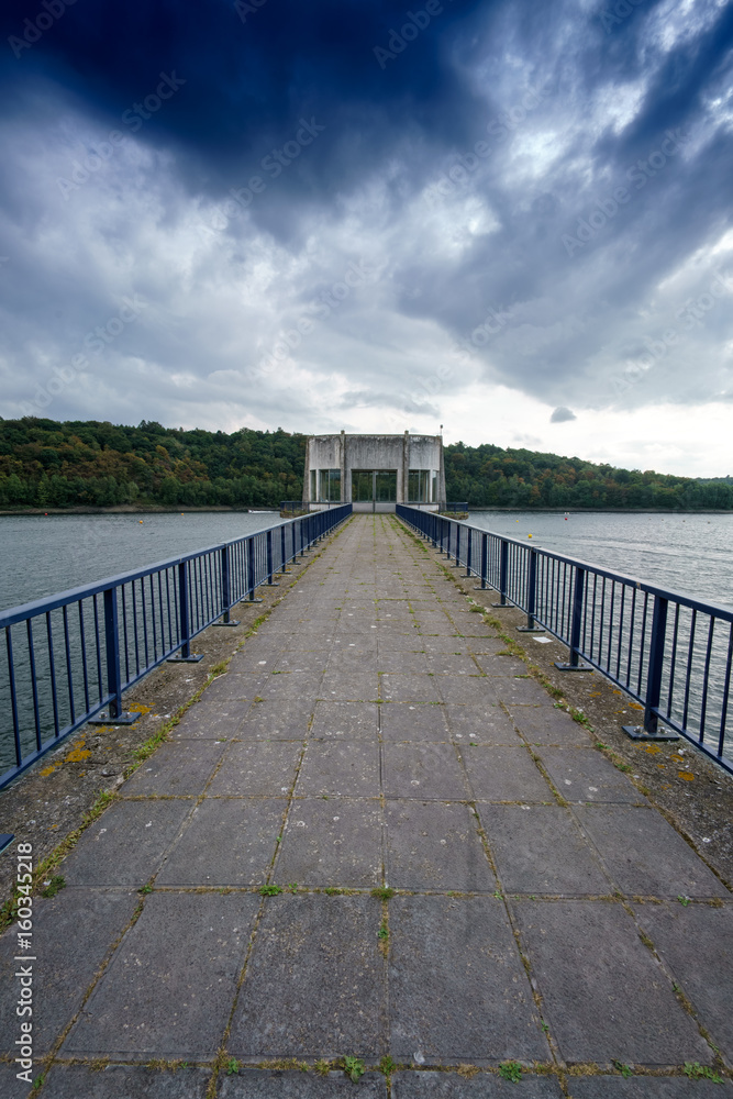 Empty pier and railings with diminishing perspective, clouds in sky, Belgium.