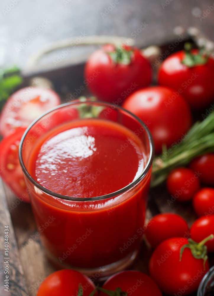 glass of tasty organic tomato juice and fresh tomatoes and herbs on wooden tray in rustic style. Selective focus, healthy lifestyle glass of tasty organic tomato juice and fresh tomatoes and herbs on wooden tray in rustic style. Selective focus, healthy lifestyle