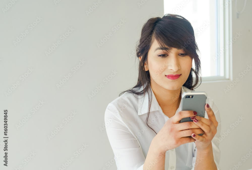 Young woman using mobile phone with laptop in kitchen at home. Young woman using mobile phone with laptop in kitchen at home.