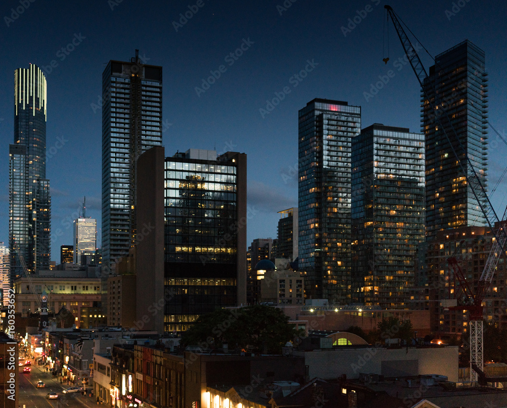 Cityscape at dusk, modern skyscrapers with illuminated windows and Ontario, Canada.