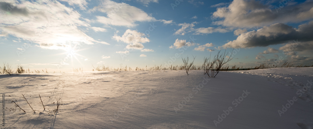 Snow covered rural landscape with bright sunlight and fluffy clouds in blue sky, Ontario, Canada. Snow covered rural landscape with bright sunlight and fluffy clouds in blue sky, Ontario, Canada.