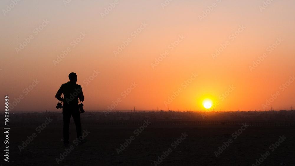 Catching the sun setting over Cairo as a photographer searches for his next shot.