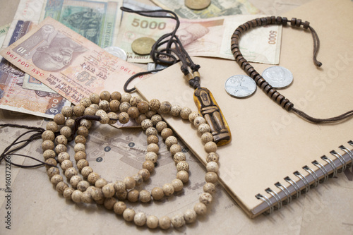 Traveling retro still life closeup with map, money, coins, buddhist mala bracelet, diary.