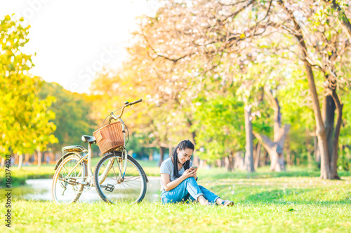 Women sit and listen to music from the smartphone in the garden and bike at sunset,She smiled happily.