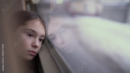 Sad child in the bus looking out the window in evening time. UHD 4K
