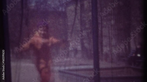 Family chronicle: Little girl child swinging on swing. Her father is recording video on 8 mm retro camera.