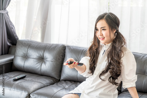 young asian woman changing tv channel at home in the living room