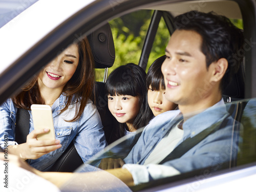 asian family enjoying a car ride, focus on the little girl. 