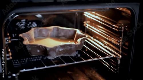 The woman puts the cake in the oven