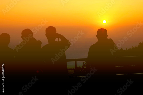 The silhouette of people look and take photo at the beauty of the sun in the morning.