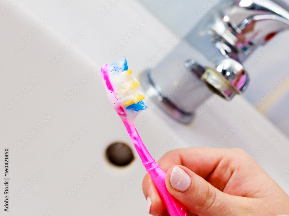 Hand holding toothbrush in bathroom