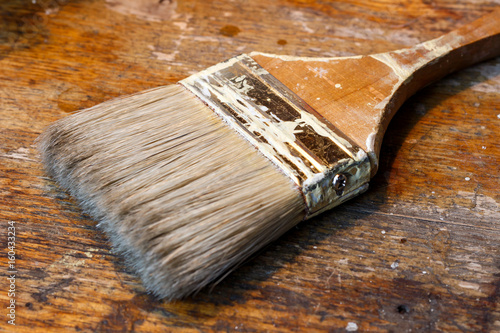 Paint brush stained with paint on the workbench photo