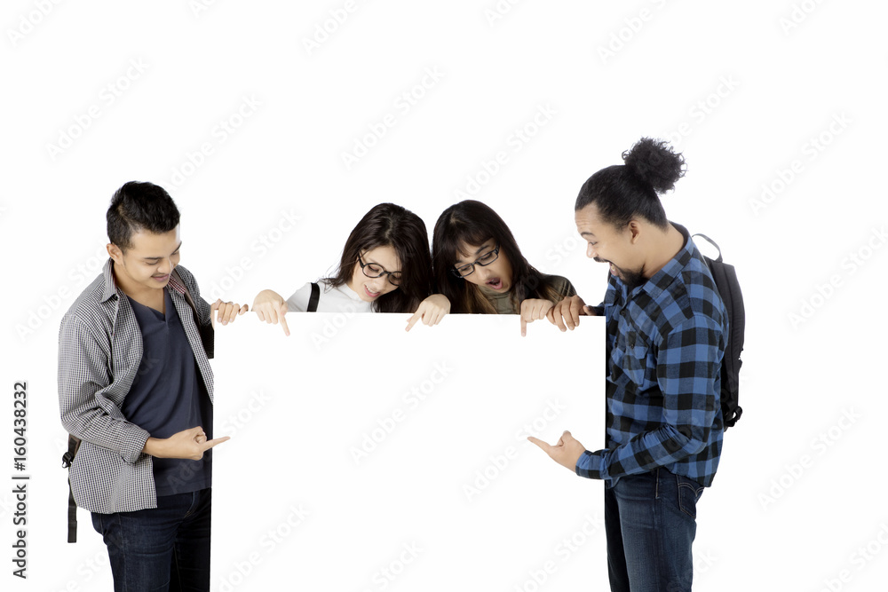Multiracial students pointing at empty banner Multiracial students pointing at empty banner