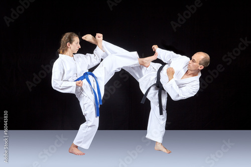 Athletes in karategi are training kicking in pairs