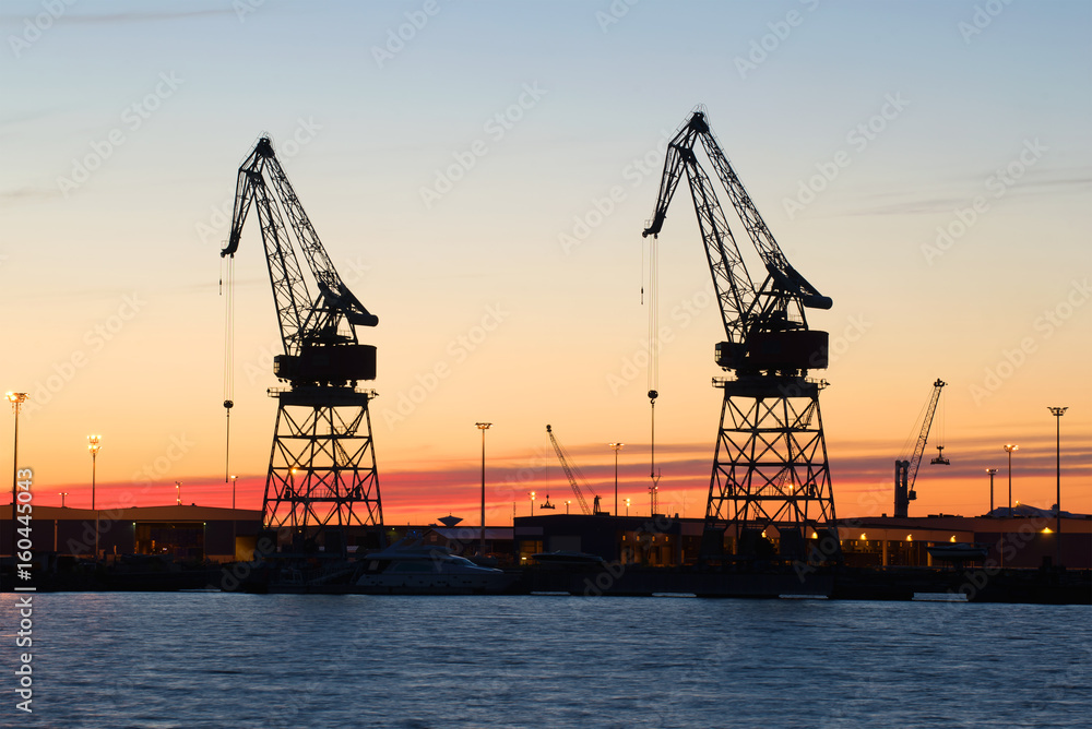 Silhouettes of two port cranes at sunset. The kargo port of Kotka. Finland
