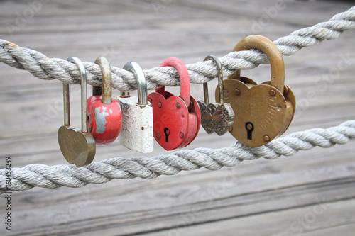 lot of different love padlocks on thick hemp rope