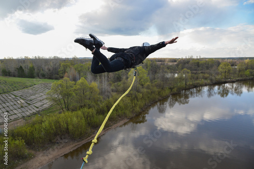 Rope jumping from high altitude of bridge. Man fly in air like an airplane.