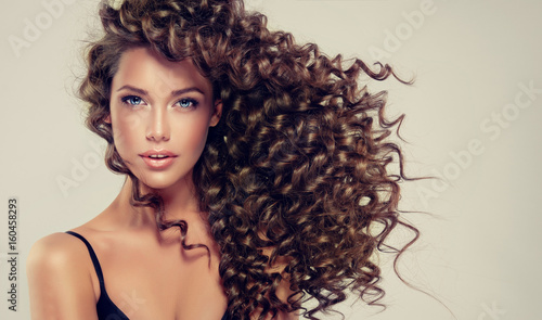 Brunette girl with long and shiny curly hair . Beautiful model with wavy hair...
