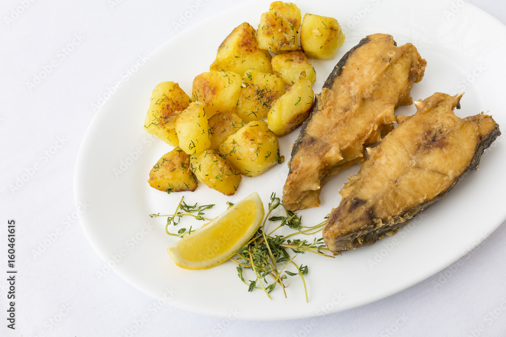 Fried fish garnished with potatoes, close up, top view at restaurant