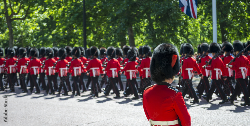 Fototapeta Soldiers in classic red coats march along The Mall in London, England in a grand Trooping the Colour spectacle of the Queen's Royal Guard