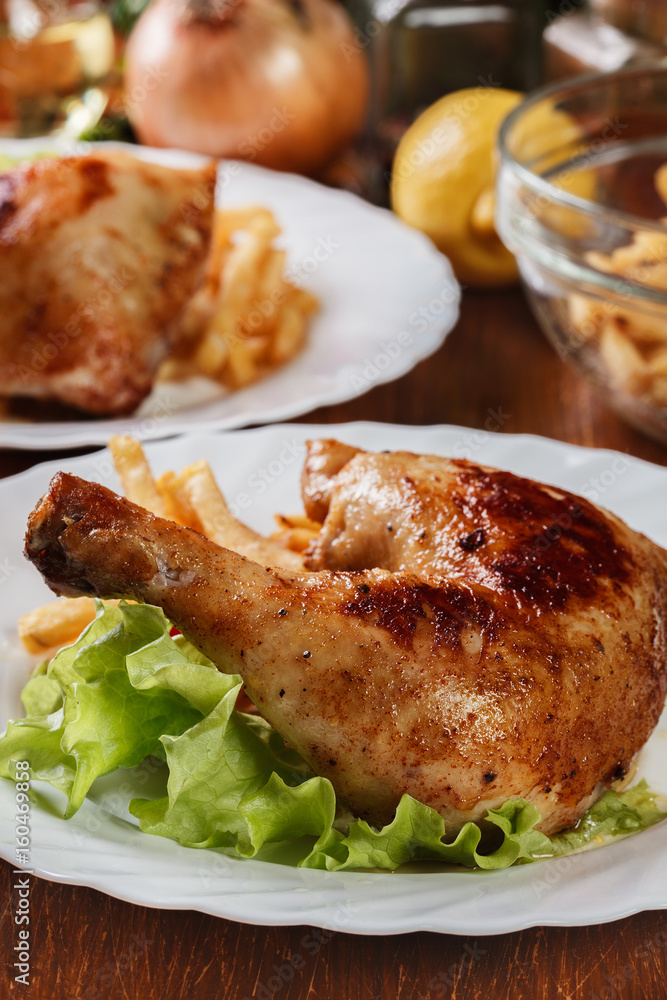 Roasted chicken legs with french fries and lettuce Roasted chicken legs with french fries and lettuce