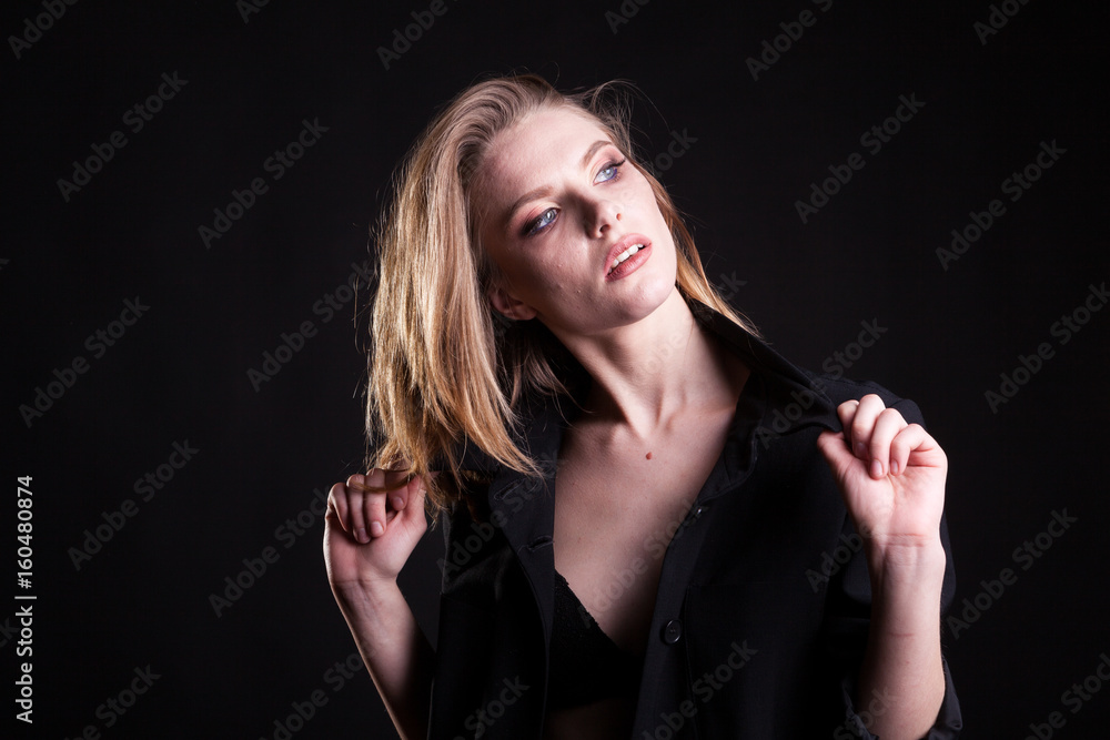 Obraz premium Beautiful blonde woman in casual fashion clothes in studio photo on black background. Sexyality and sensuality