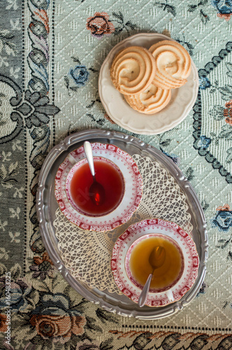 Two cup of the in a silver tray with biscuits from above photo