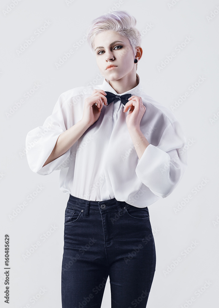 Attractive girl in white shirt and black jeans corrects her bow tie on white  background. Fashion photo. Studio portrait. Stock Photo | Adobe Stock