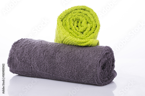 Two towels gray and green twisted into a roll on a white background