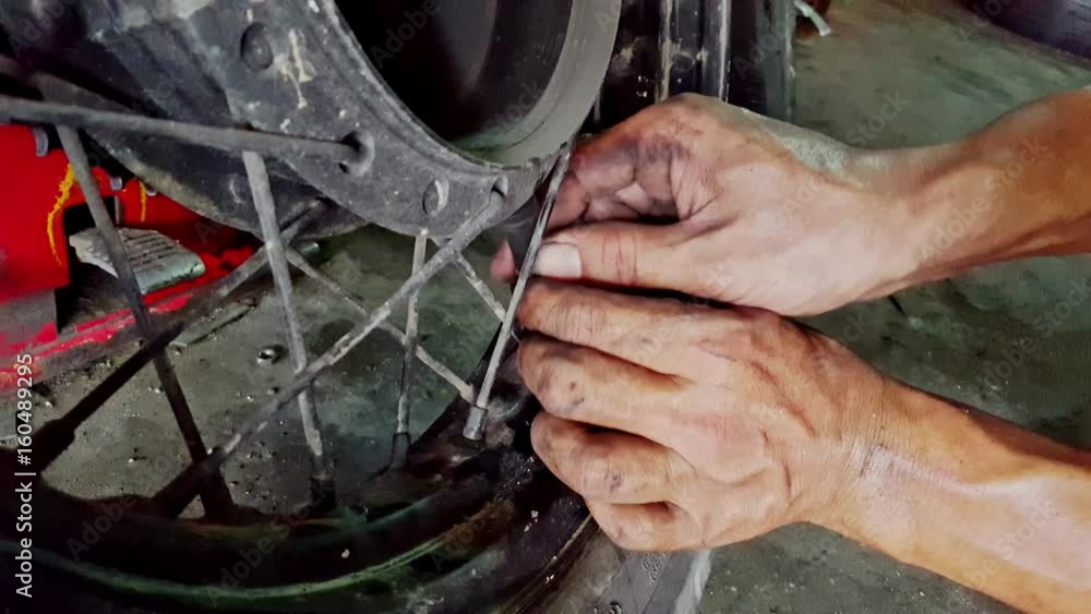 Closeup Man Hands Fasten Detail to Tire Disk in Shop Closeup Man Hands Fasten Detail to Tire Disk in Shop