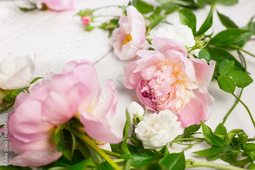 Close up of pink and white flowers on wooden table. Peonies and wild roses. High key  copy space.