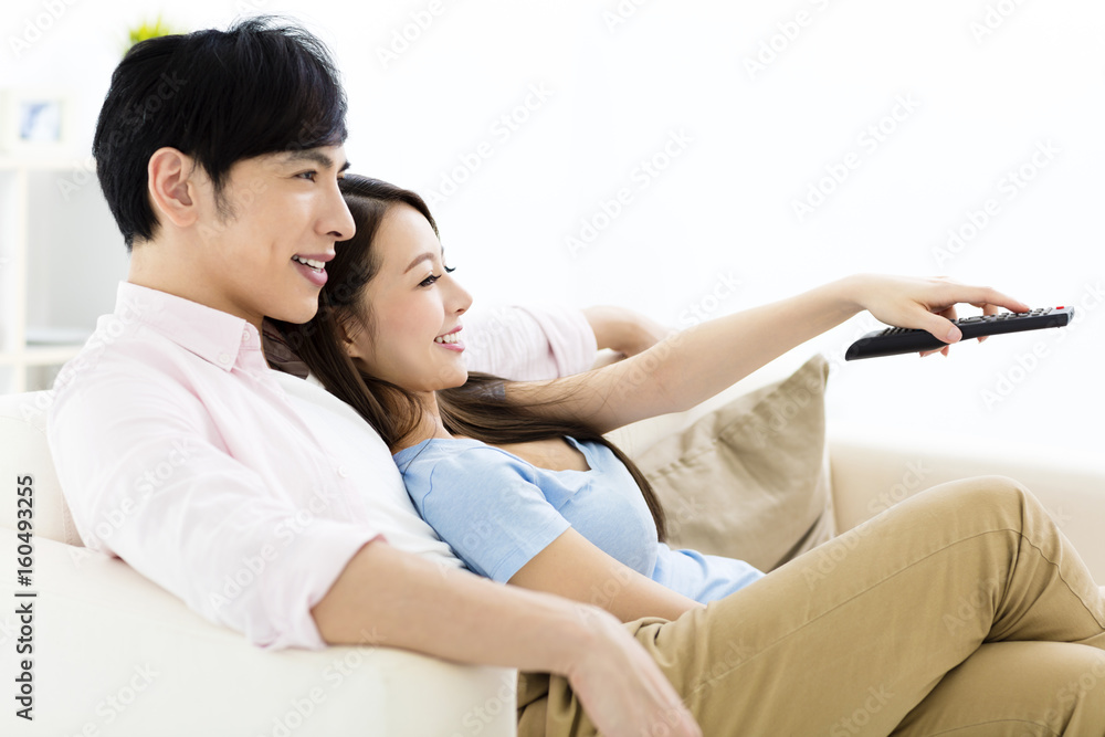 smiling young couple watching tv in living room smiling young couple watching tv in living room