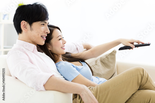 smiling young couple watching tv in living room