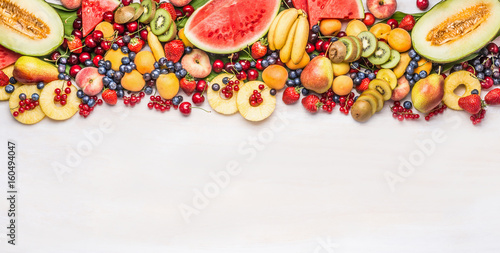 Fototapeta Naklejka Na Ścianę i Meble -  Variety of colorful organic fruits and berries on white table background, top view, border. Healthy food and vegetarian eating concept
