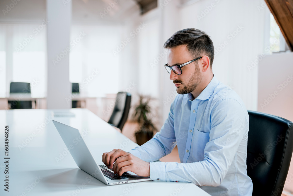Businessman sitting at office desk working on laptop computer Businessman sitting at office desk working on laptop computer