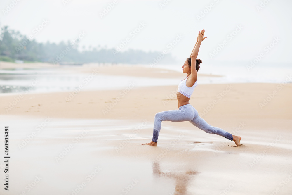 Caucasian woman practicing yoga at seashore of tropic ocean Caucasian woman practicing yoga at seashore of tropic ocean