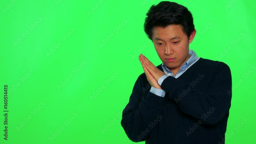 A young Asian man sleeps with the head on his hands which are clasped together, then he wakes up and stretches - green screen studio A young Asian man sleeps with the head on his hands which are clasped together, then he wakes up and stretches - green screen studio