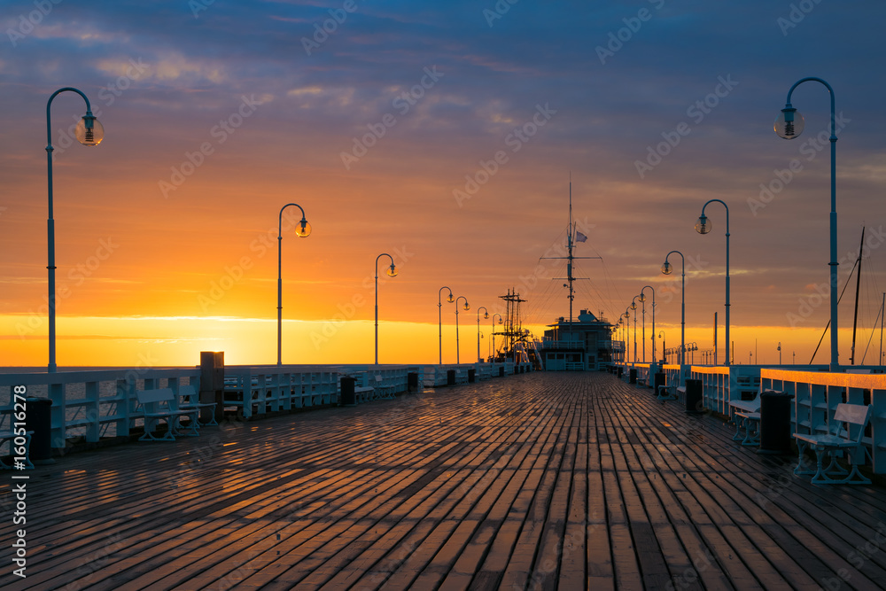 The first rays of the sun warms the wet boards of the pier in Sopot. Poland.