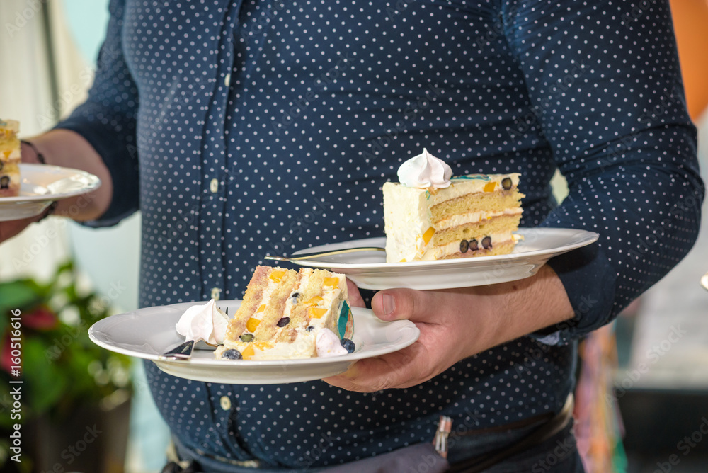 Waiter carries plates with desserts of cakes