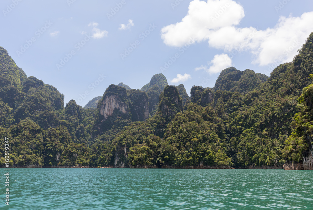 Shore of Ratchaprapha lake with tropical trees on a sunny day Shore of Ratchaprapha lake with tropical trees on a sunny day