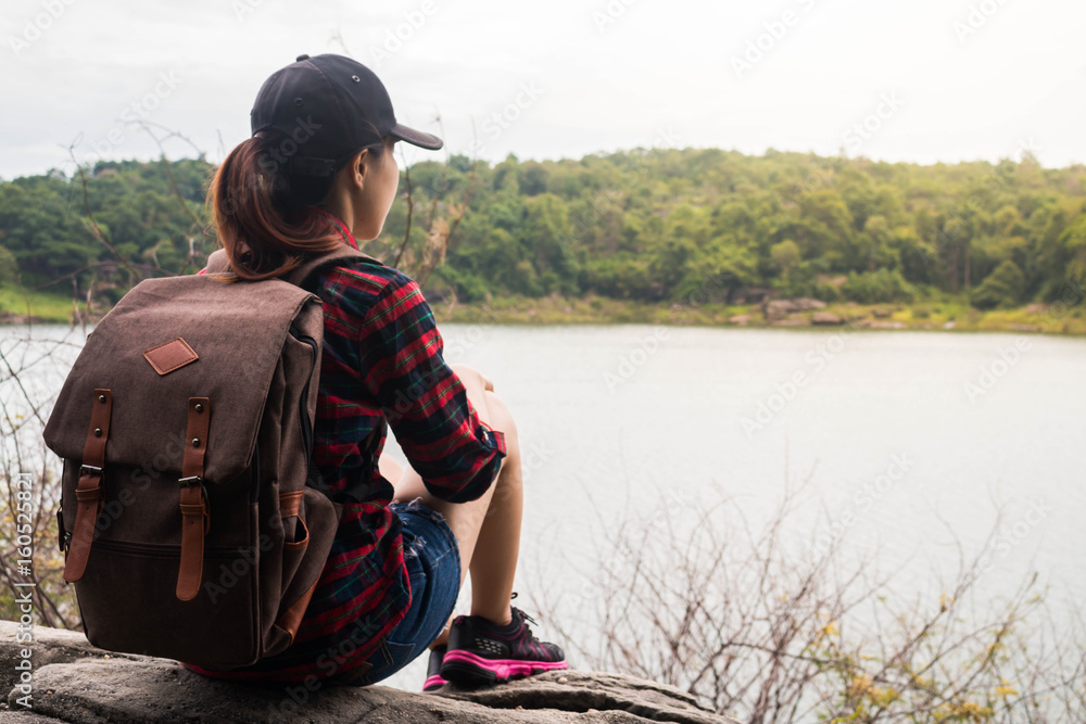 Woman with backpack sit by the the riverside. Woman with backpack sit by the the riverside.