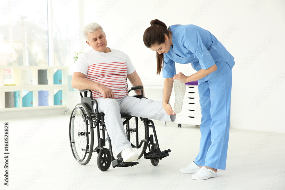 Senior disabled man with young orthopedist in rehabilitation clinic Senior disabled man with young orthopedist in rehabilitation clinic